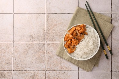 Photo of Bowl of delicious rice with meat, mushrooms and chopsticks on tiled table, top view. Space for text