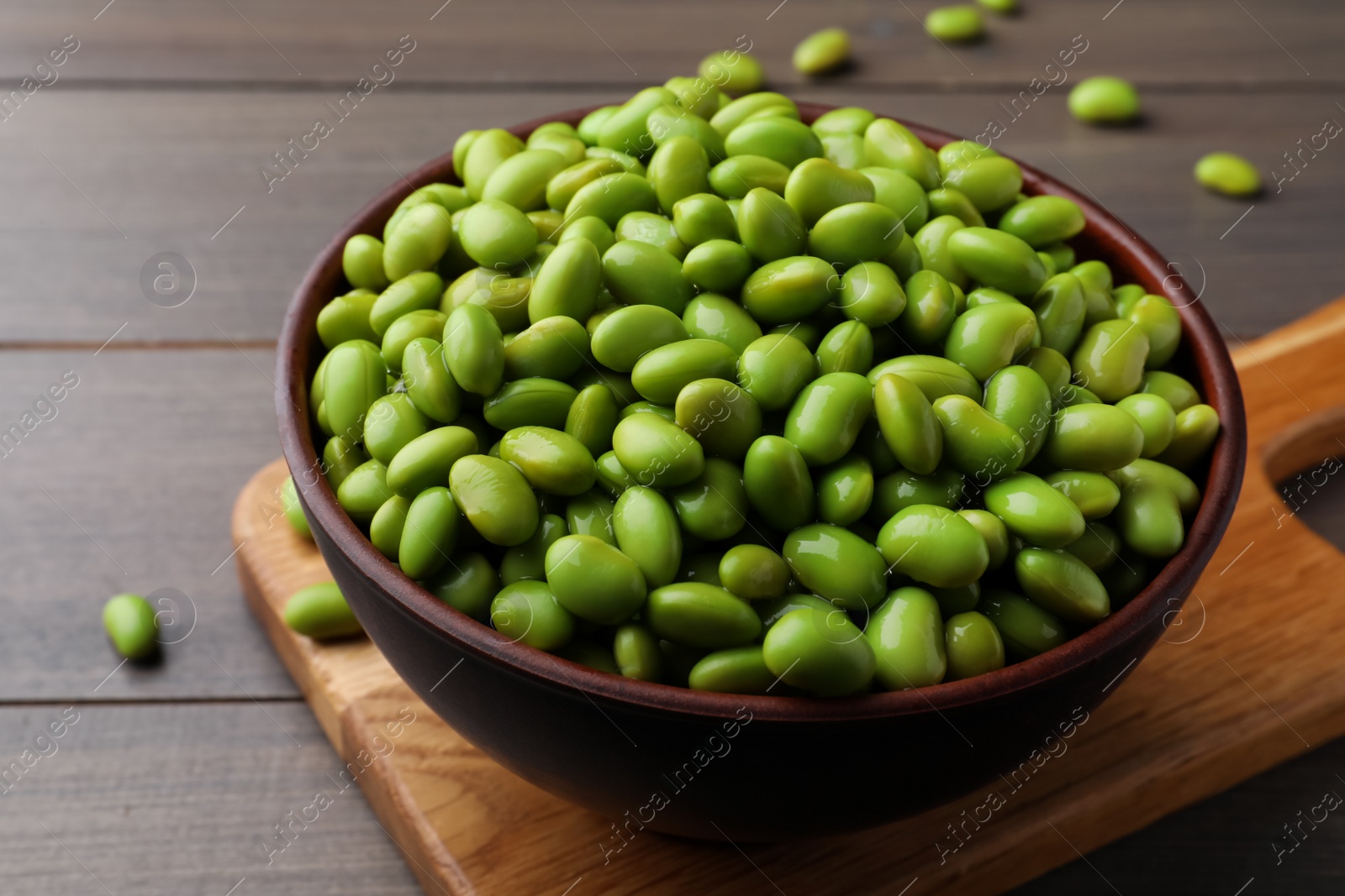 Photo of Bowl of delicious edamame beans on wooden table, closeup