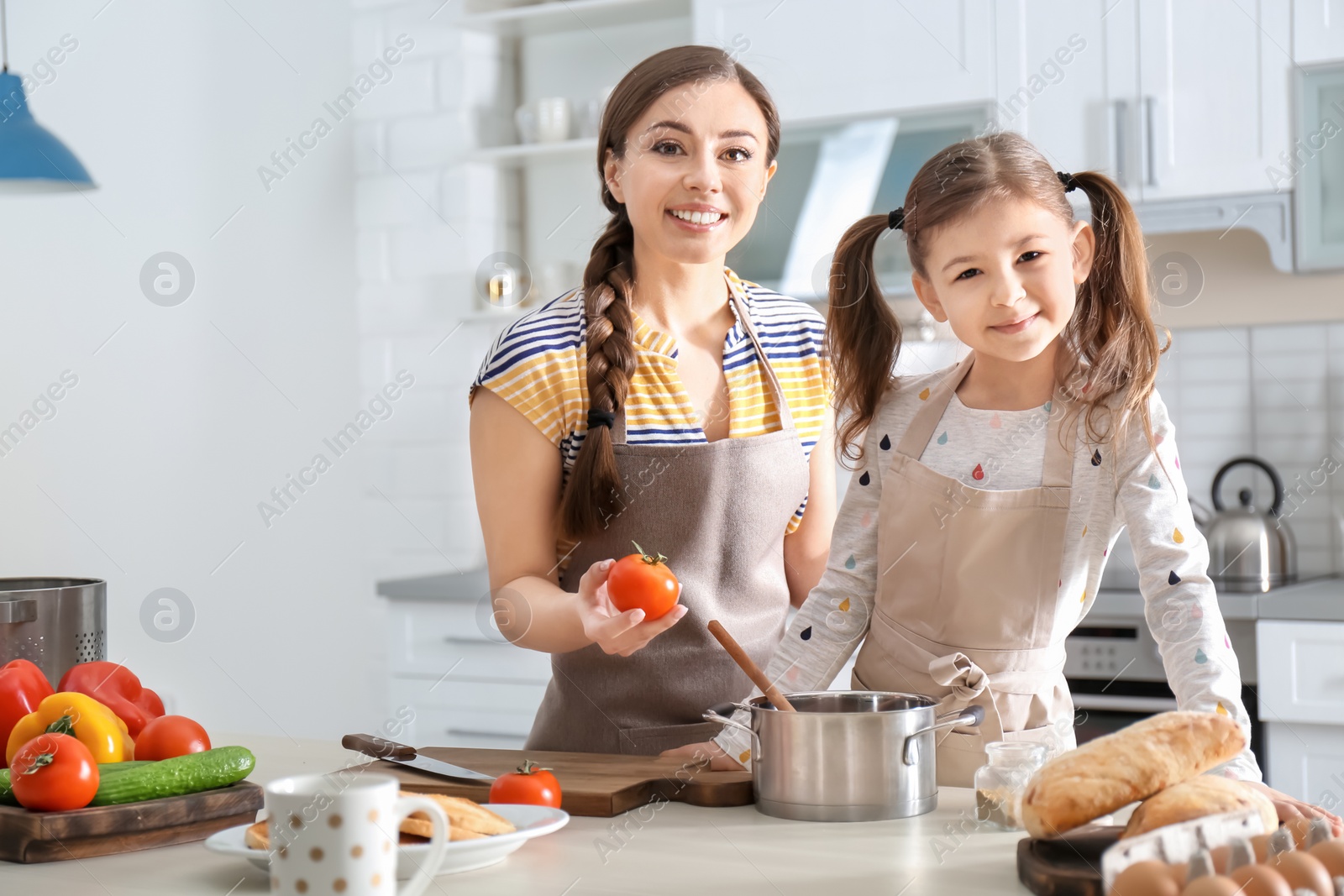 Photo of Young nanny with cute little girl cooking together in kitchen