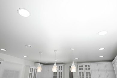 Photo of Modern pendant lamps on white ceiling indoors