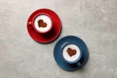Photo of Cups of aromatic coffee with heart shaped decoration on light grey table, flat lay