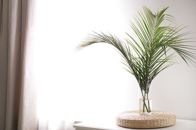 Photo of Green tropical leaves in vase on table. Modern decor for stylish interior