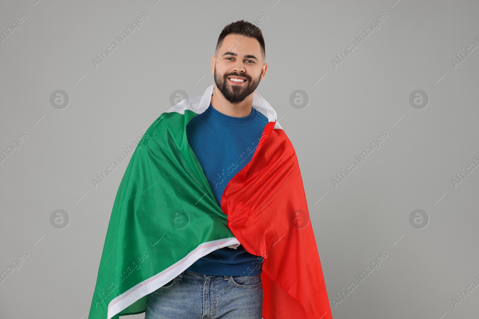 Photo of Young man with flag of Italy on light grey background, space for text