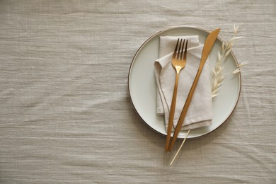 Stylish setting with cutlery, napkin and plate on light table, top view. Space for text
