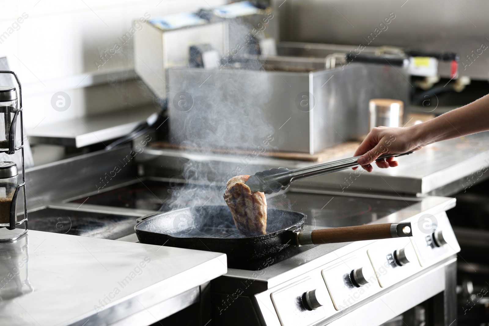 Photo of Female chef cooking chicken fillet on stove in restaurant  kitchen, closeup