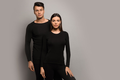 Photo of Couple wearing thermal underwear on grey background. Space for text