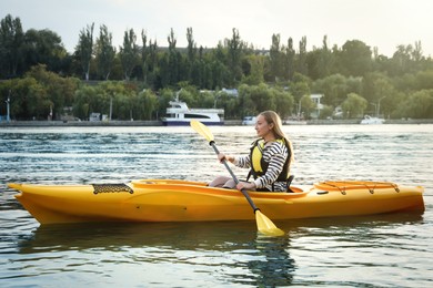 Beautiful young woman kayaking in river. Summer activity