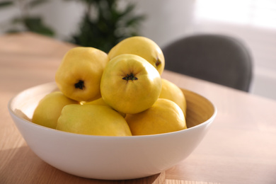 Ripe quinces on wooden table at home, closeup