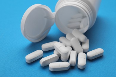 Antidepressants and medical bottle on light blue background, closeup