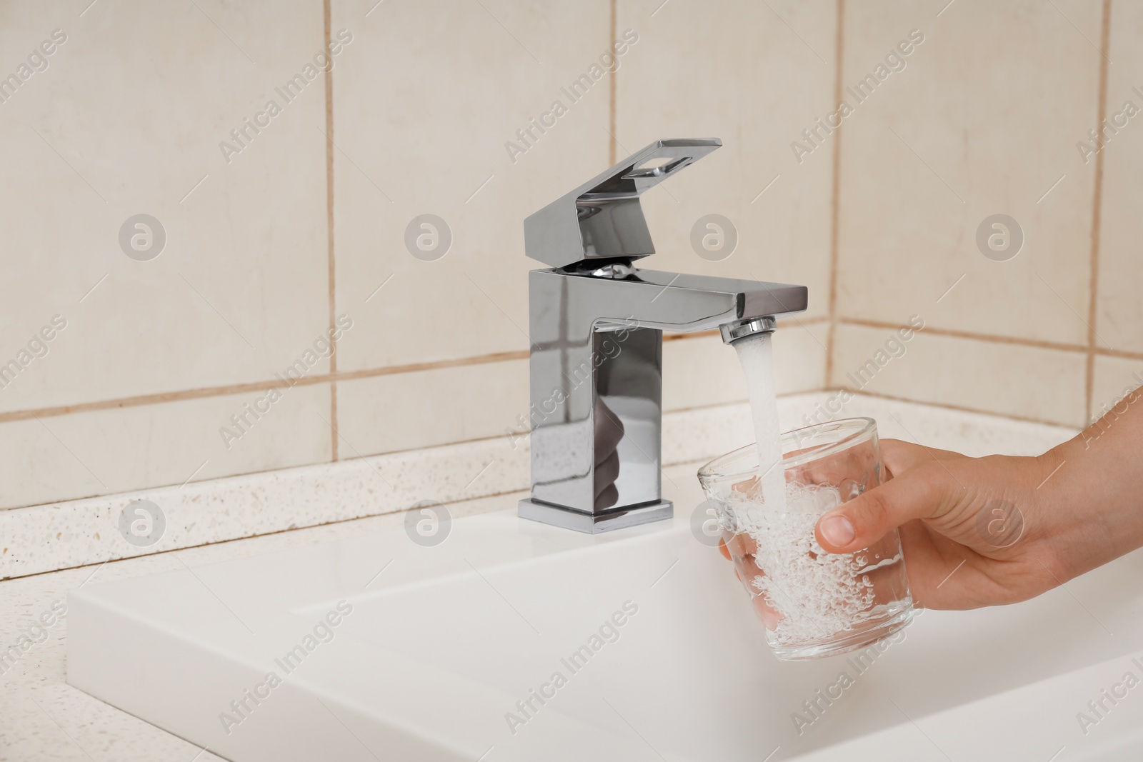 Photo of Woman filling glass with water from faucet indoors, closeup