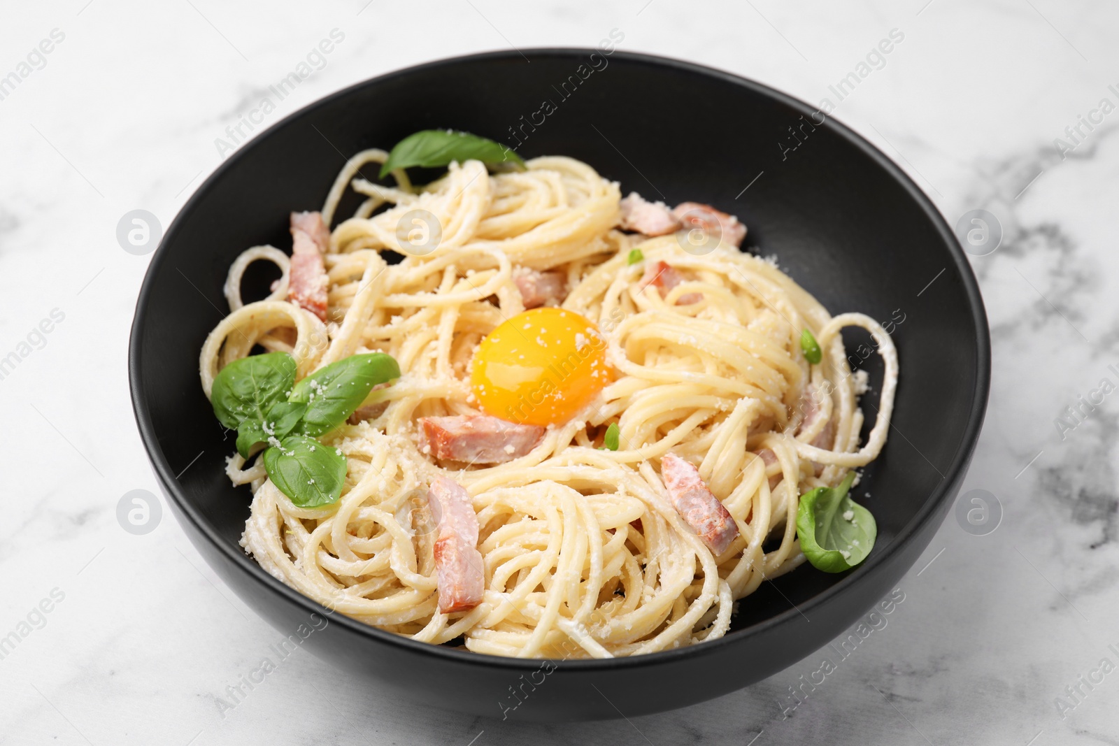 Photo of Delicious pasta Carbonara with egg yolk on white marble table, closeup