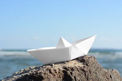 Photo of White paper boat on rock near sea