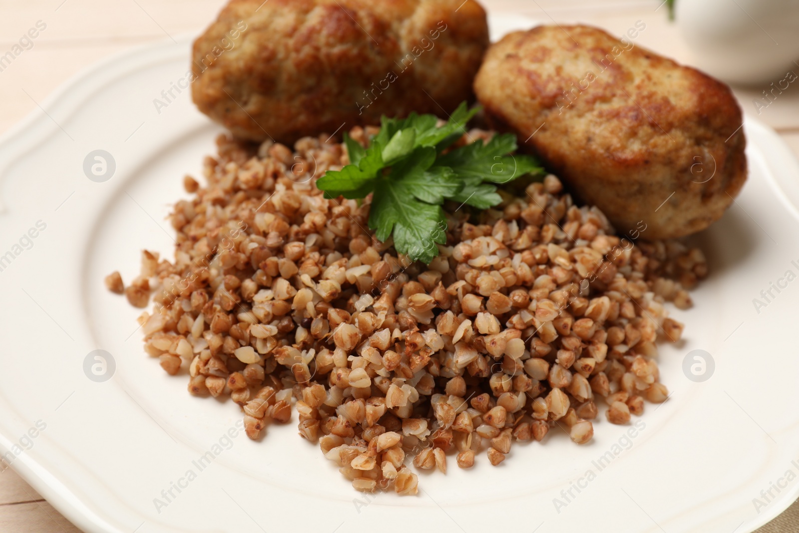Photo of Tasty buckwheat with fresh parsley and cutlets on plate, closeup