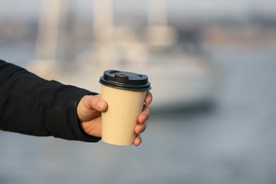 Photo of Man holding paper coffee cup outdoors, closeup. Space for text