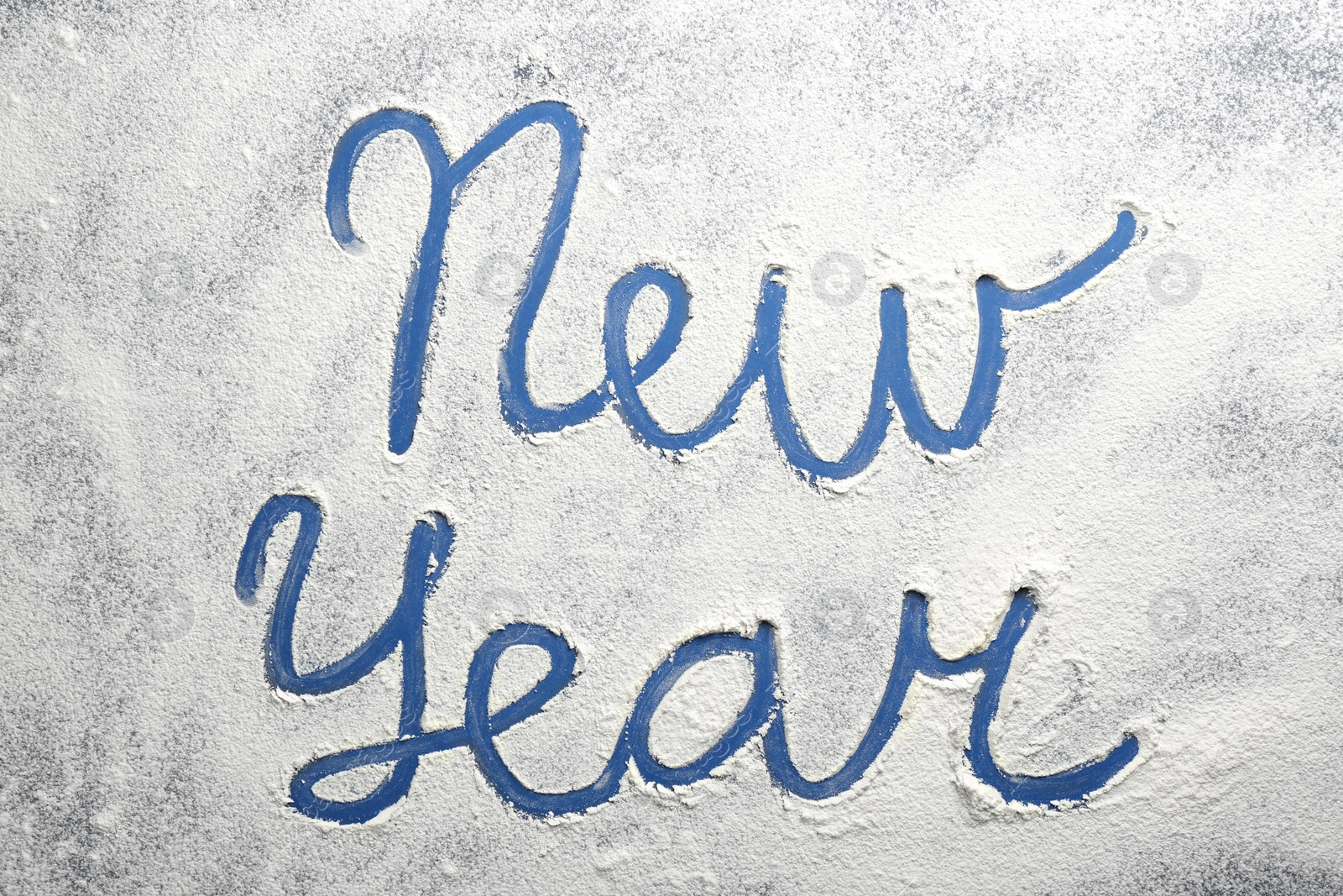 Photo of Words New Year made of flour on blue background, top view