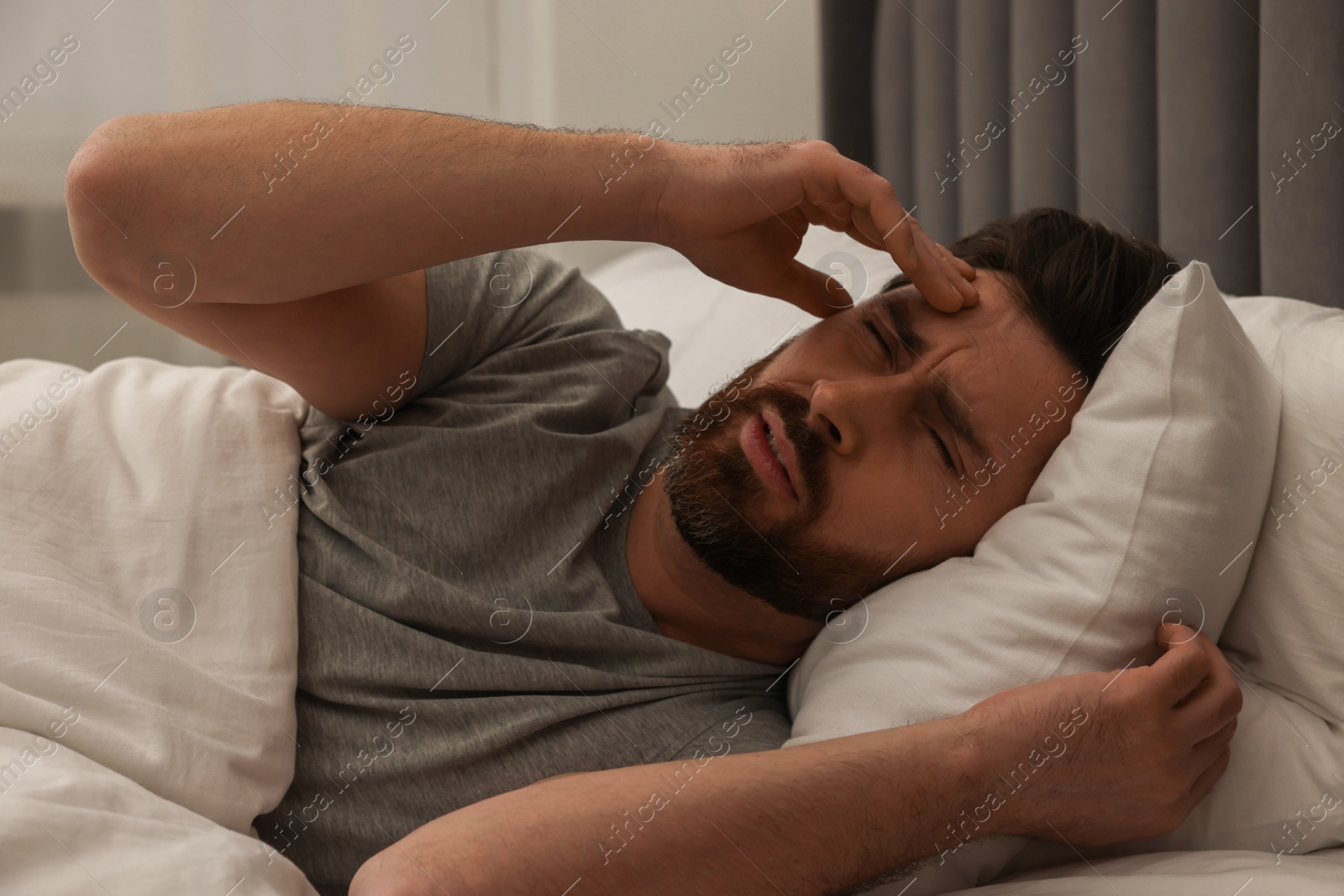 Photo of Man suffering from headache in bed at night