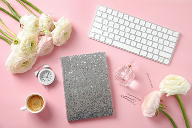 Flat lay composition with glittering notebook, keyboard and spring flowers on color background