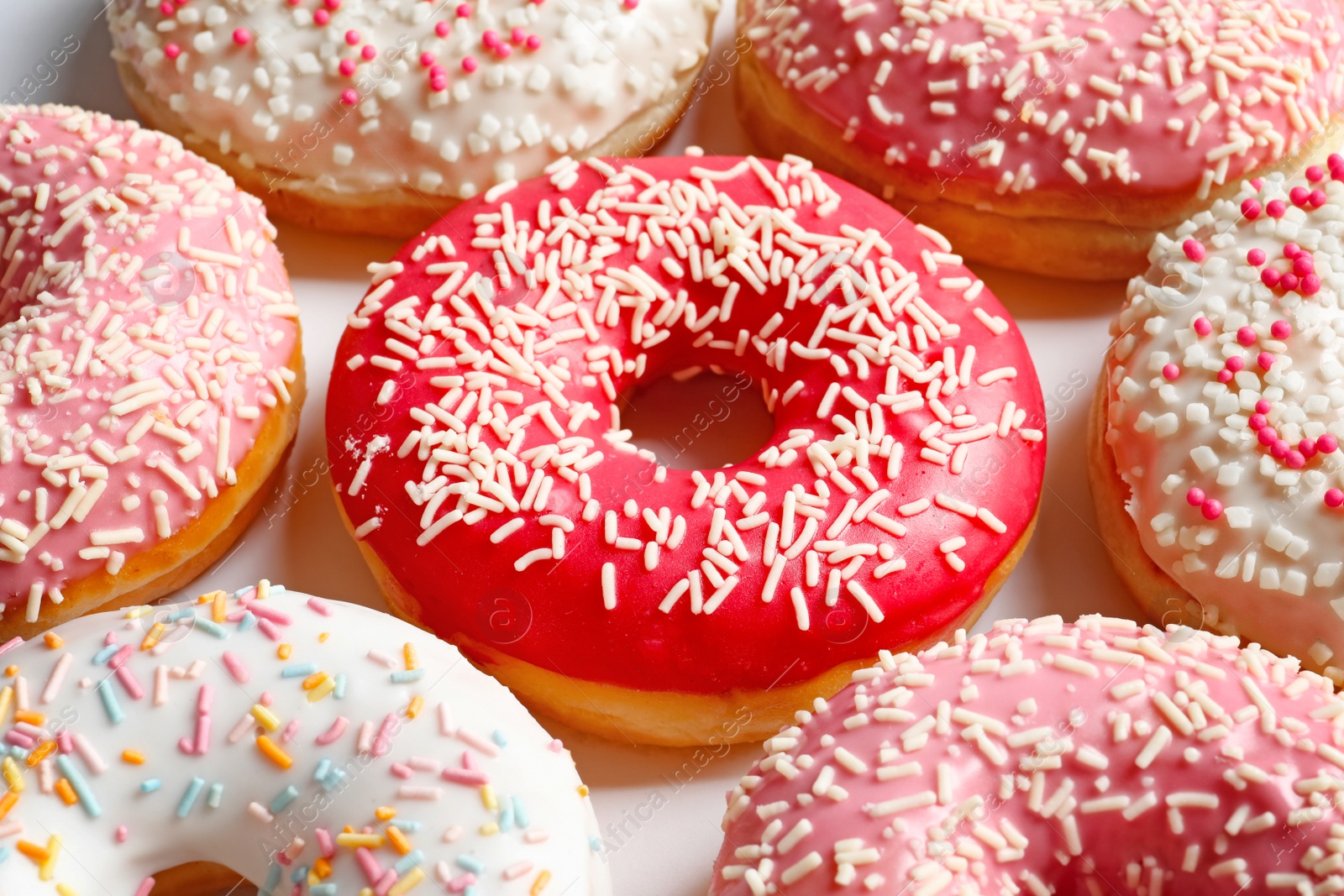 Photo of Delicious glazed doughnuts with sprinkles on light background