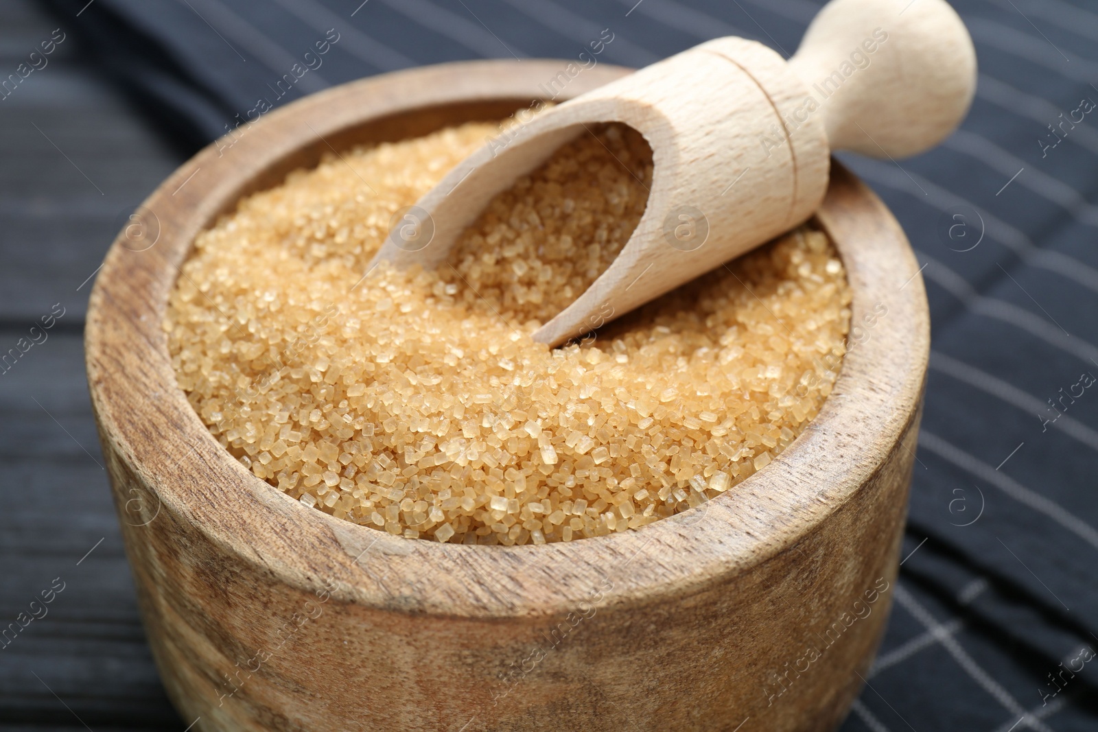 Photo of Brown sugar in bowl and scoop on table, closeup