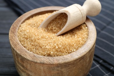 Photo of Brown sugar in bowl and scoop on table, closeup