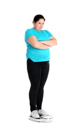 Overweight woman in sportswear using scales on white background
