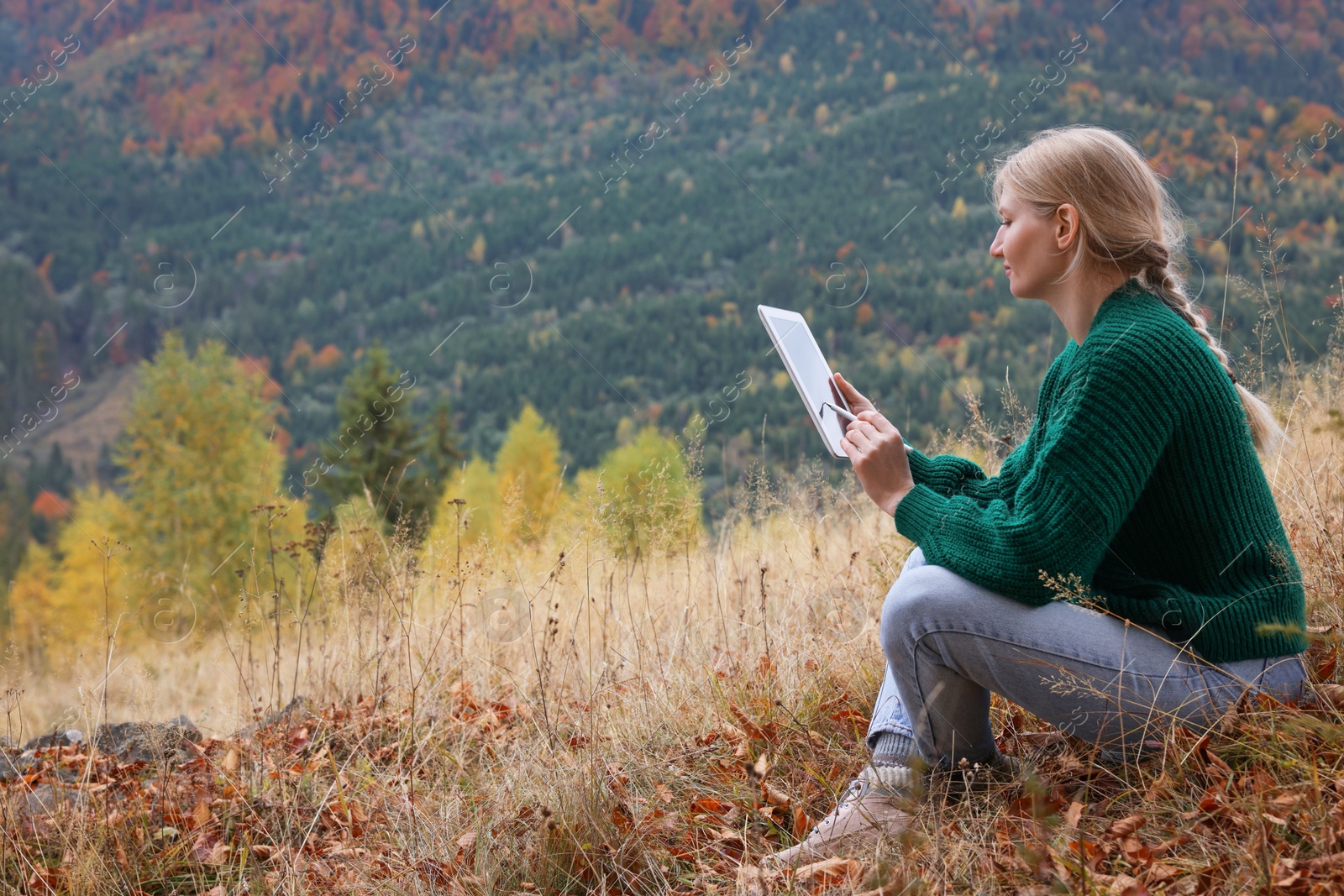 Photo of Young woman drawing on tablet in mountains, space for text