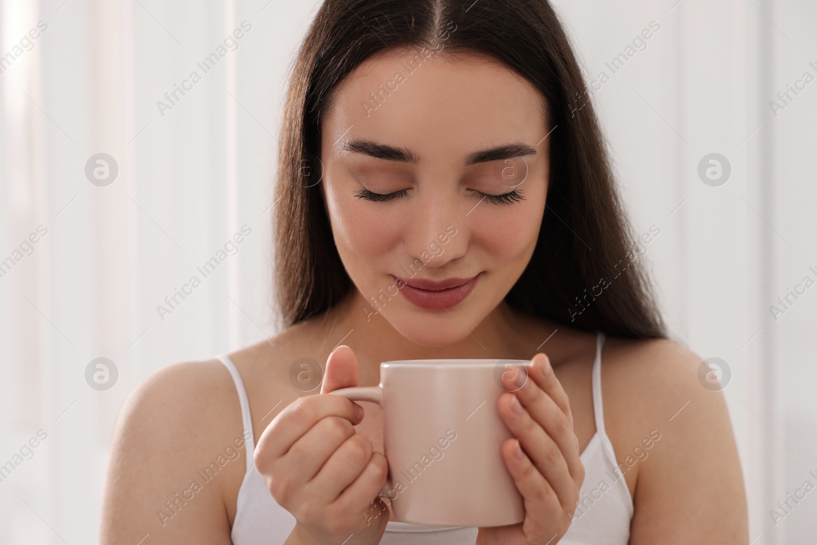 Photo of Smiling woman with cup of drink indoors. Lazy morning
