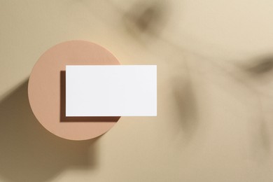 Empty business card and decorative podium on beige background, top view. Space for text. Mockup for design