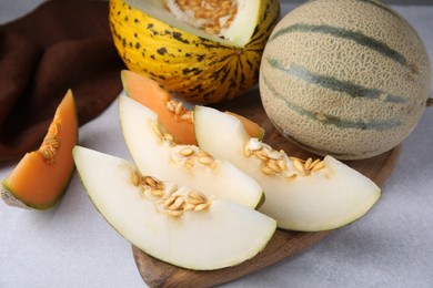 Photo of Tasty colorful ripe melons on light grey table