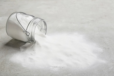 Overturned jar with baking soda on grey background. Space for text