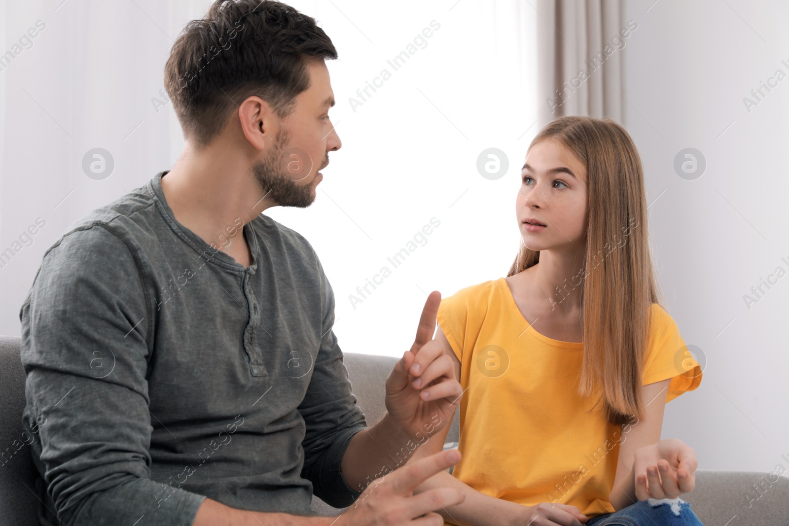 Photo of Father talking with his teenager daughter at home