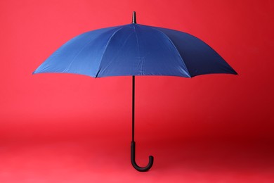 Stylish open blue umbrella on red background