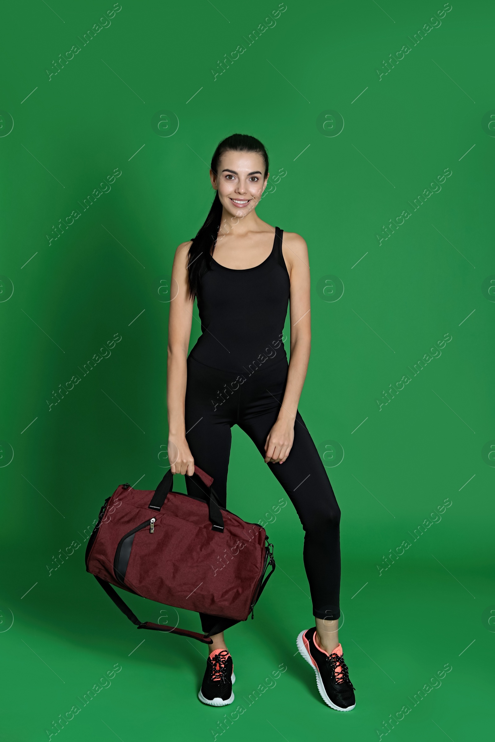 Photo of Beautiful woman with sports bag on green background