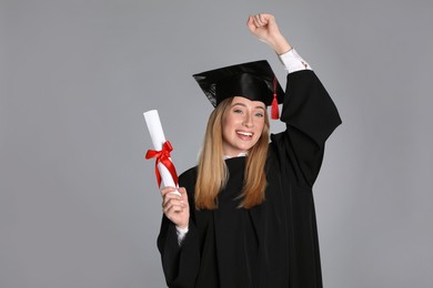 Happy student with diploma on grey background