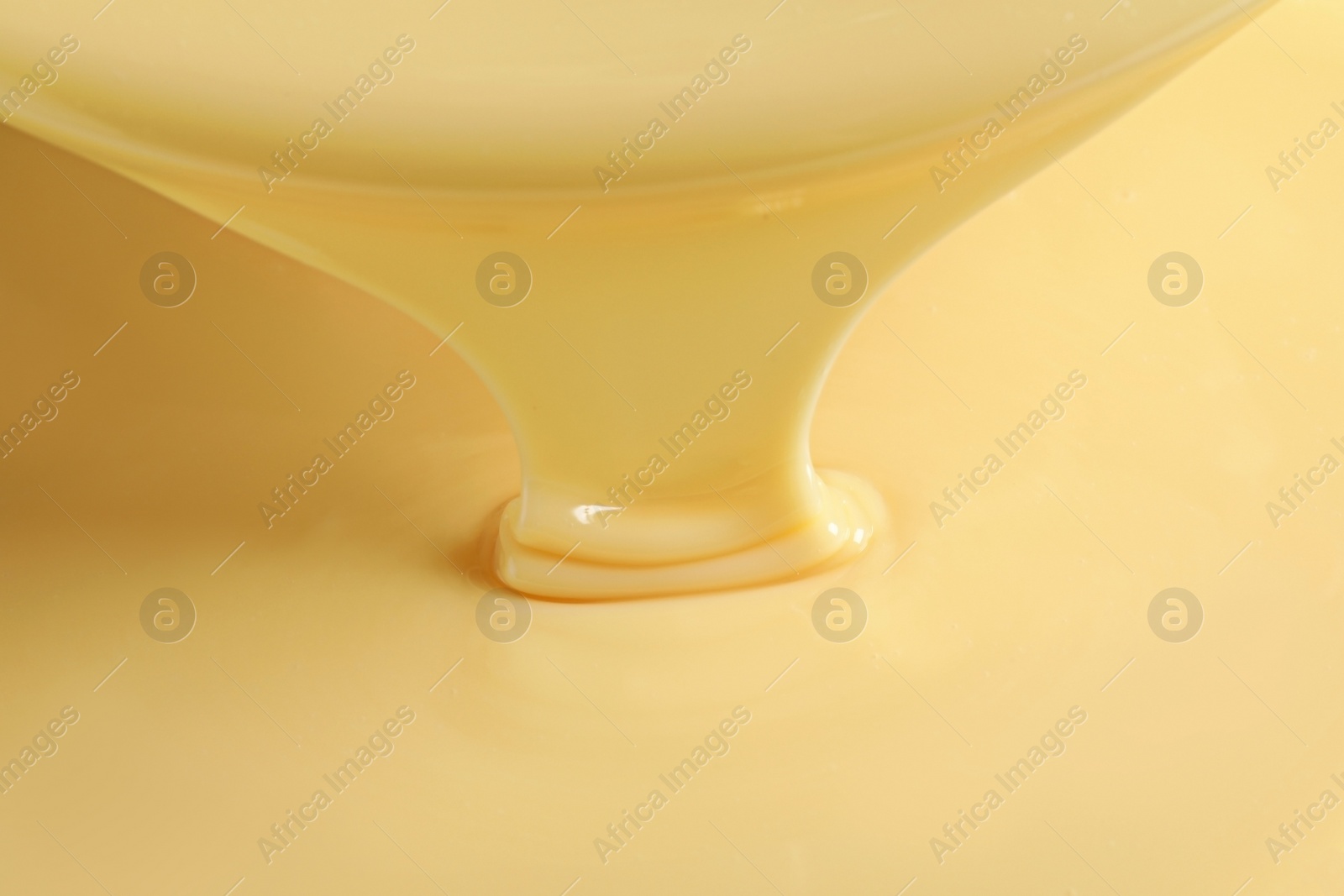 Photo of Tasty pouring condensed milk as background, closeup. Dairy product