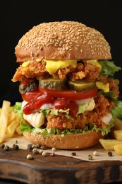 Delicious burger with crispy chicken patty and french fries on table, closeup