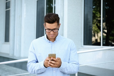 Photo of Handsome man using modern mobile phone outdoors