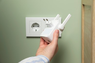 Photo of Woman holding wireless Wi-Fi repeater indoors, closeup