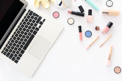 Flat lay composition with makeup products for woman and laptop on white background