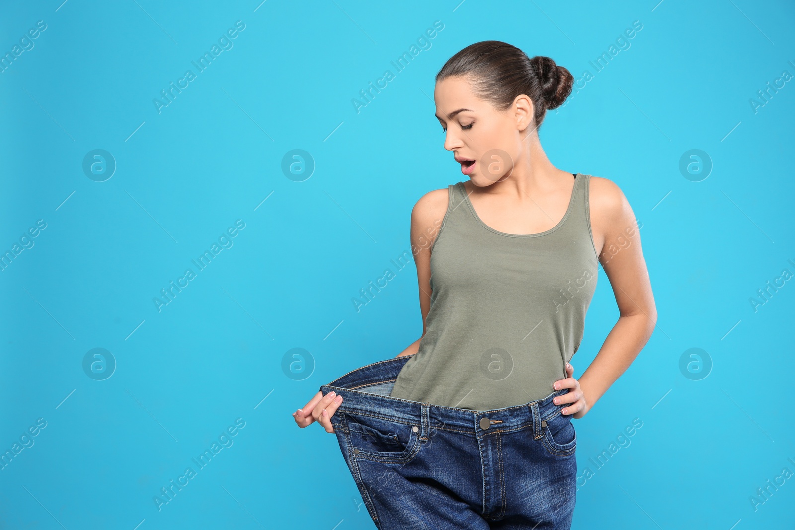 Photo of Slim woman in oversized jeans on color background, space for text. Weight loss