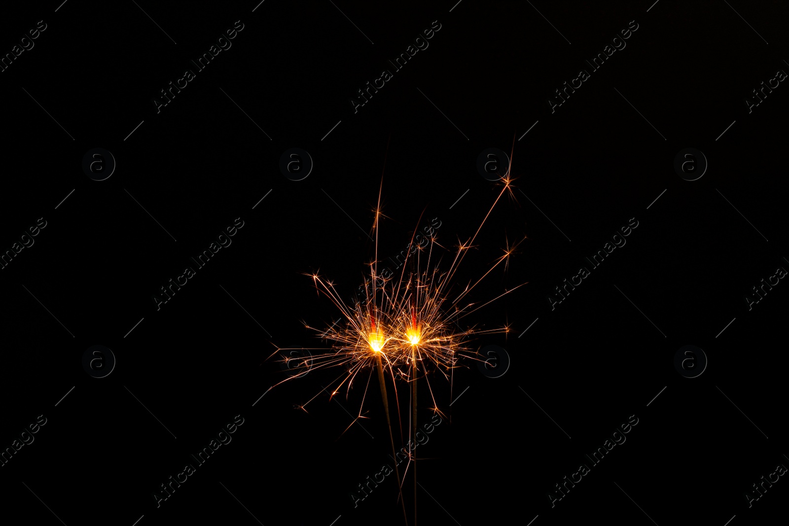 Photo of Two burning sparkler sticks glowing in dark