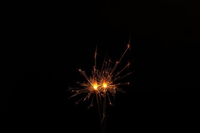Photo of Two burning sparkler sticks glowing in dark