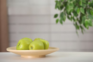 Photo of Plate with fresh green apples on white wooden table indoors, space for text