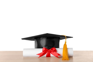 Graduation hat and diploma on table against white background