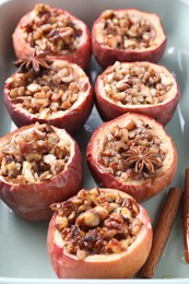 Tasty baked apples with nuts, honey and spices in dish, closeup