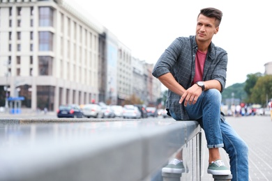 Photo of Portrait of handsome young man on city street. Space for text