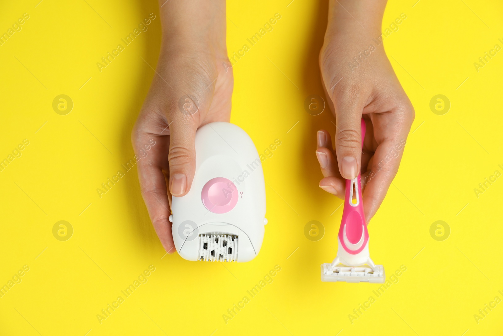 Photo of Woman holding modern epilator and razor on yellow background, top view