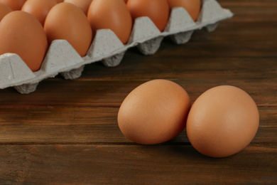 Photo of Raw brown chicken eggs on wooden table