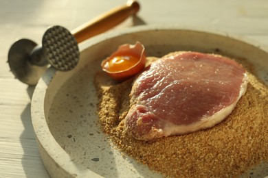 Photo of Cooking schnitzel. Raw pork chop, meat mallet and ingredients on white wooden table, closeup