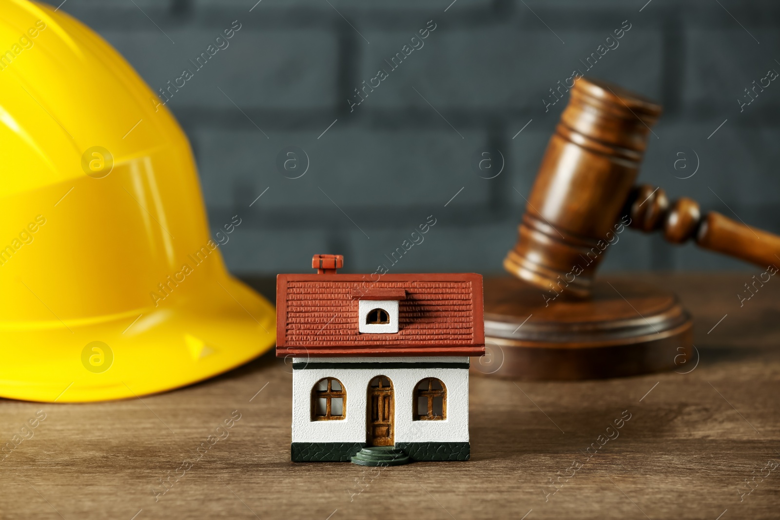 Photo of Construction and land law concepts. House model, gavel and hard hat on wooden table, closeup